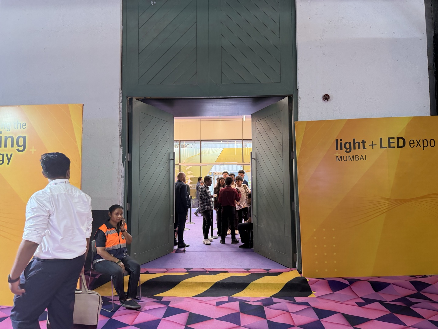 Group of visitors converging at the main access point — caution carpet threshold between designer carpet zones at Light + LED Expo Mumbai