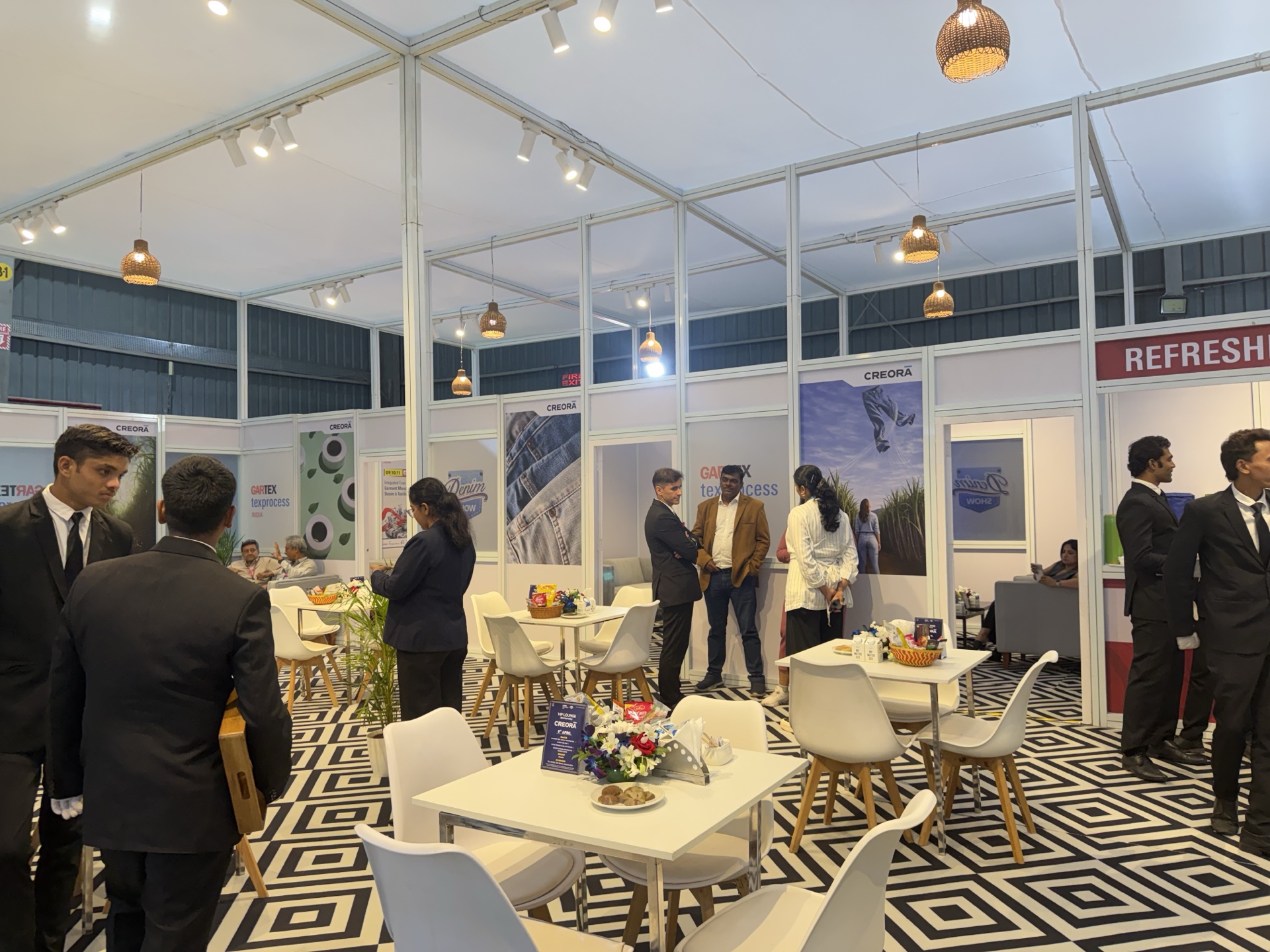Exhibition refreshment lounge — bold black and white diamond harlequin printed carpet covering the full hospitality zone floor