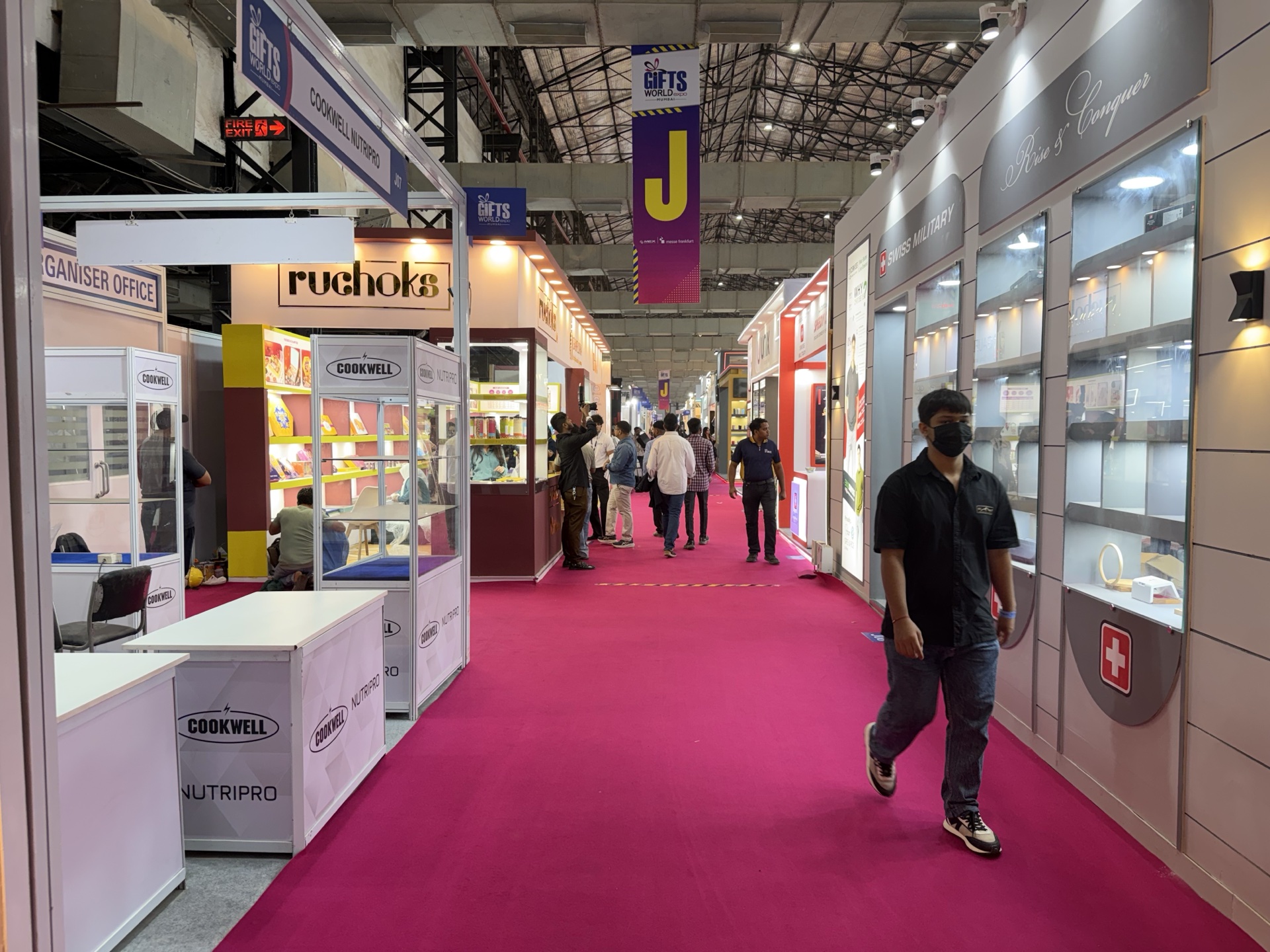Pink non woven carpet running through a trade fair corridor — booths lining both sides