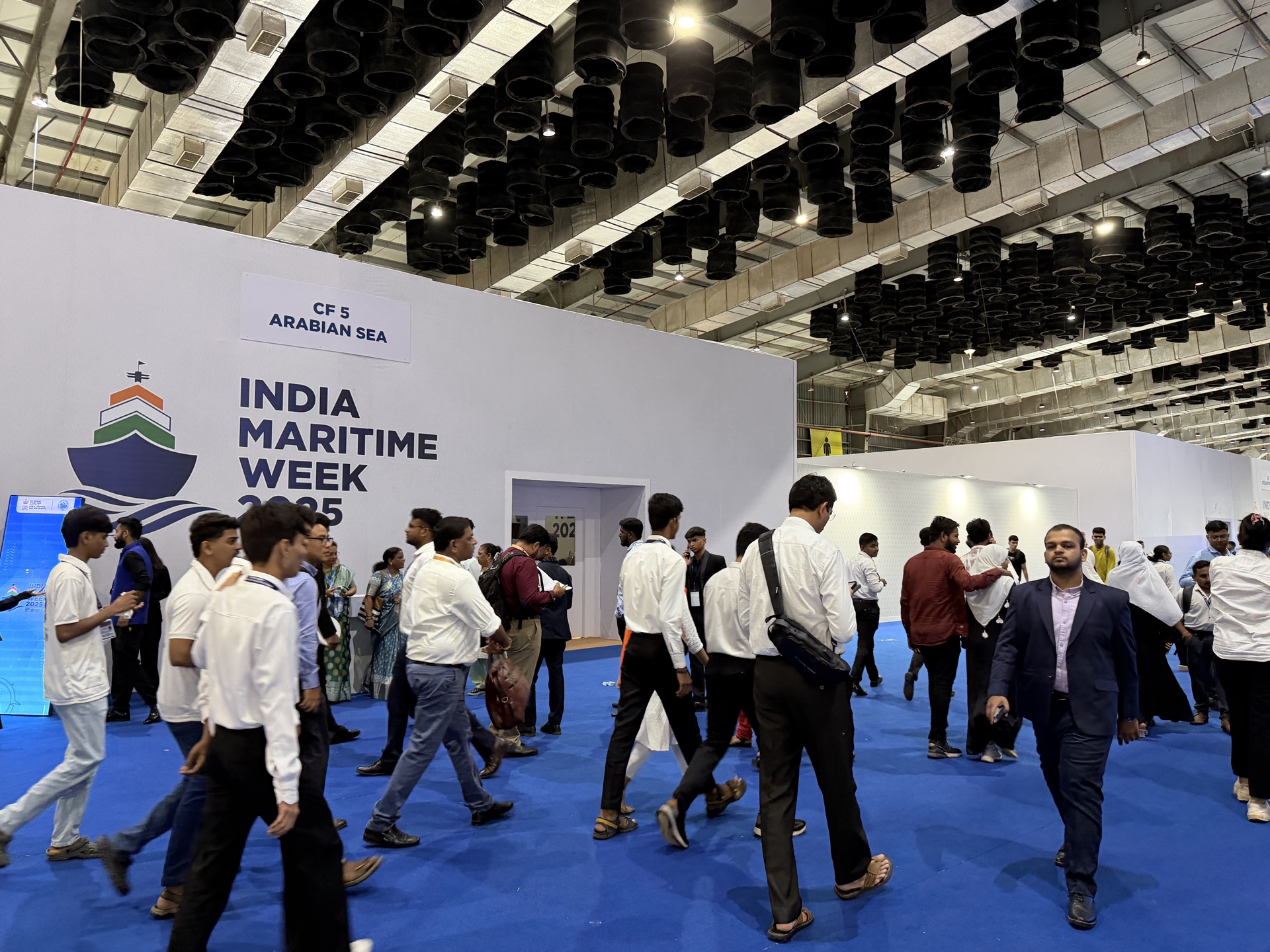 Blue non woven carpet at India Maritime Week 2025 — large crowd on exhibition floor